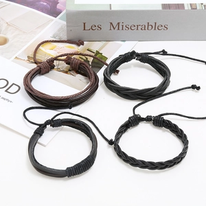 Set of four multilayer woven leather bracelets in black and brown on white surface