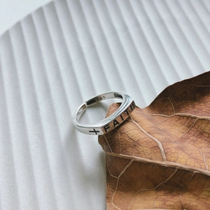 Close-up of S925 sterling silver Faith cross ring on a brown leaf with white background