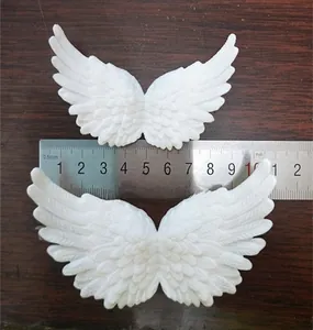 Detailed view of white plastic angel wings with feather texture on dark wood background