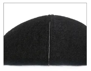 Macro shot of vertical stitching detail on the crown of a black wool blend newsboy cap