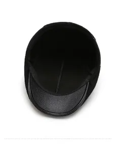 Detail view of black wool flat cap featuring lychee texture leather brim and inner lining