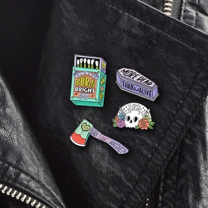 Gothic enamel pins featuring skull and coffin designs pinned on a black leather jacket