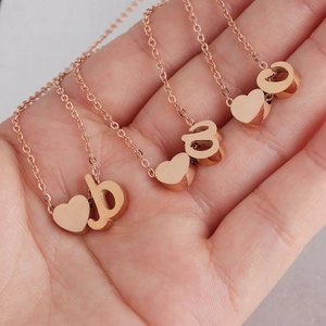 Polished rose gold heart and letter charm necklace in hand display for women