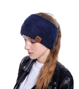 Détail d'un bandeau en maille torsadée bleu marine avec un écusson en cuir MOK