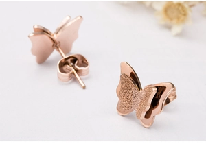 Vista detallada de los pendientes mariposa oro rosa con texturas mate y pulidas