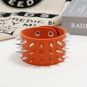 Detail of orange leather punk bracelet with three rows of silver metal cone spikes