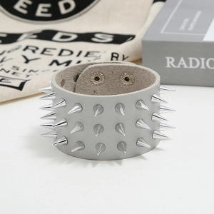 Close-up of gray leather punk bracelet with triple-row silver cone spikes and snap buttons