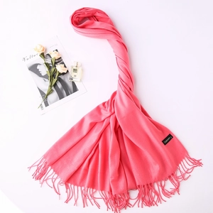 Detailed view of soft pink cashmere scarf with fringe tassels and luxury lifestyle props