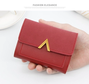 Detail of red lychee grain leather wallet with a golden V-shape buckle held by hand