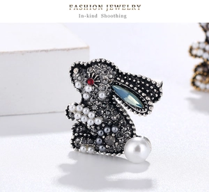 Detail of vintage rabbit brooch featuring grey crystals, blue gemstone ears and pearls