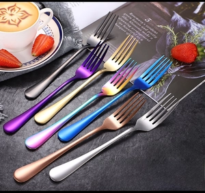 Set of colorful stainless steel dessert forks in various finishes on a cafe table