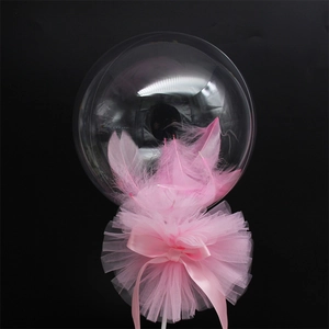 Close-up of a clear 5-inch balloon filled with pink feathers, lace and ribbon details