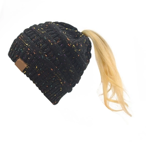 Dettaglio del berretto in maglia nera con coriandoli colorati e foro per coda di cavallo