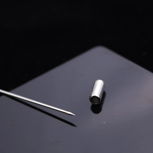 Polished silver leaf feather lapel pin with needle and cap on black background