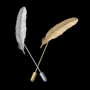 Macro shot of silver and gold feather lapel pins with detailed texture on black background