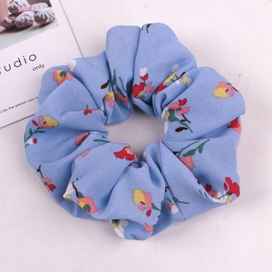 Detailed view of light blue floral scrunchie with delicate chiffon and small flower prints