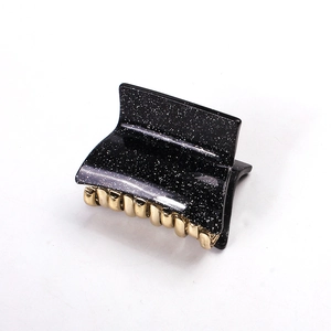 Detail of black glitter claw clip with golden metal teeth for stylish hair styling