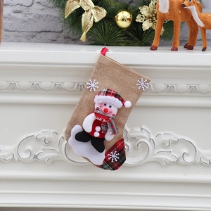 Detail of burlap Christmas stocking with snowman figure hanging on a festive mantel