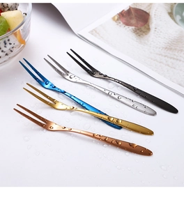 Close-up of five colorful two-prong stainless steel fruit forks with creative water drop effect