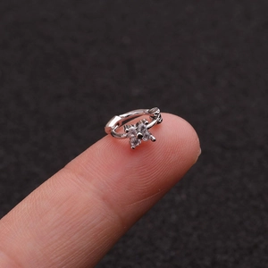 Close-up of a silver flower ear cuff with zircon stones held on a fingertip
