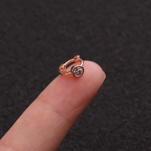 Close-up of rose gold cartilage earring with sparkling crystal on a fingertip