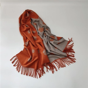 Detail of double-sided camellia cashmere scarf in orange and grey with soft tassels