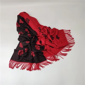 Detail view of red and black jacquard rose pattern scarf with fringe on soft cashmere fabric
