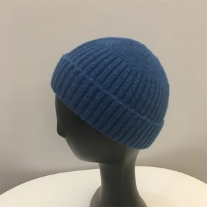 Detail of blue mohair knit beanie featuring a vertical ribbed texture on a black display stand