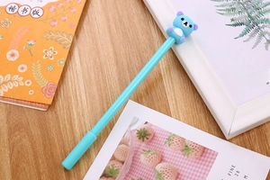Close-up of blue cartoon bear gel pen placed on a rustic wooden desk with books