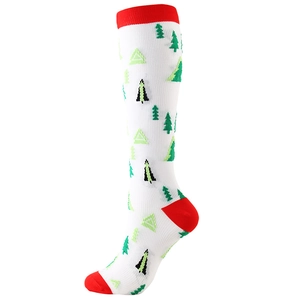 Christmas compression socks with festive green tree patterns and red toe accents on white
