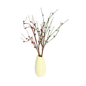 Artificial red and green berry branches in a white ceramic vase for Christmas home decor