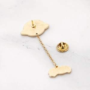 Detail of gold star and planet enamel pin back with metal chain on marble texture