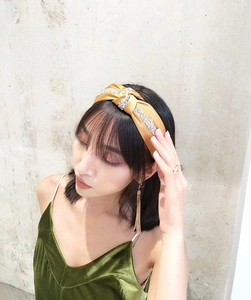 Detail of yellow satin twisted headband featuring two rows of sparkling rhinestones