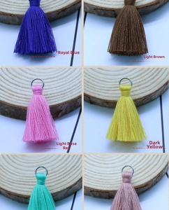 Detail of multi-color 3.5cm cotton tassels with metal rings on wooden display slices