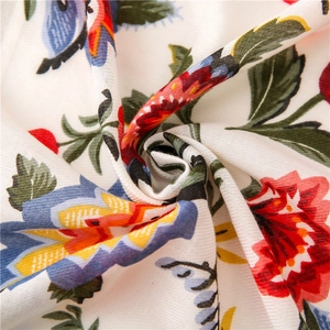 Detailed macro view of colorful floral print on white cotton-linen shawl fabric texture