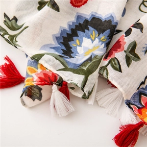 Macro detail of floral print linen scarf with vibrant patterns and decorative tassels