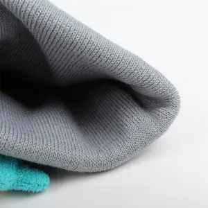 Detail of grey chunky knit beanie showing thick stitch texture and elastic fabric detail