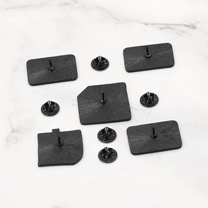 Black metal enamel pin backs with rubber butterfly clutches set on marble background