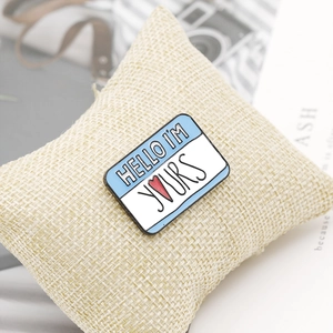 Macro shot of Hello I'm Yours enamel pin on a beige cushion with vintage camera background