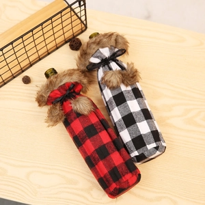 Detail of red and white buffalo check wine bottle covers with faux fur collars on wood