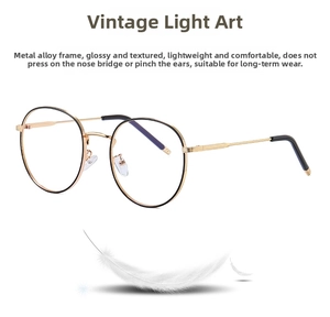 Detail of round retro metal glasses in black and gold placed on a feather for lightweight display