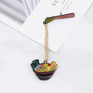 Creative ramen noodle enamel pin with gold chain connection on marble background