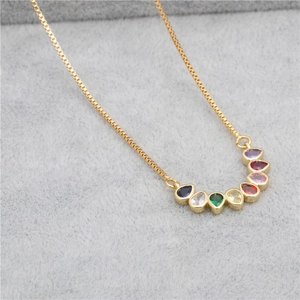 Close-up of golden necklace with curved colorful teardrop gemstones on velvet background