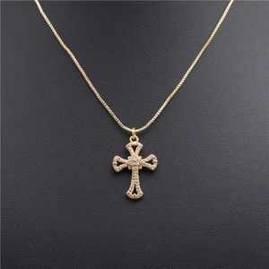 Gold cross necklace with micro-pave cubic zirconia on a black textured background