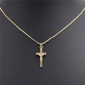 Detail view of a gold cross pendant with Jesus figure and zircons on a box chain