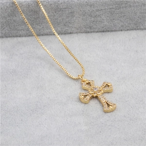 Detail shot of a gold-plated cross pendant with inlaid zircons on a gray velvet surface