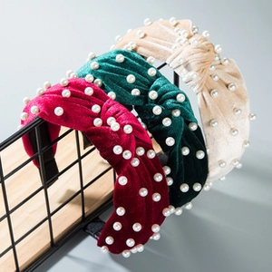 Detail of wide velvet headbands with knot design and embedded faux pearls in three colors