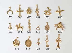 Collection of 17 different 18K gold plated titanium steel pendants on white background
