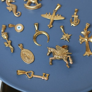 Detailed overhead view of assorted 18K gold plated titanium steel charms on a blue tray
