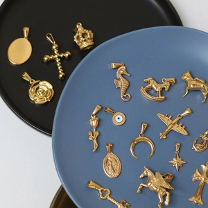Detailed view of various 18K gold-plated titanium steel charms on ceramic plates